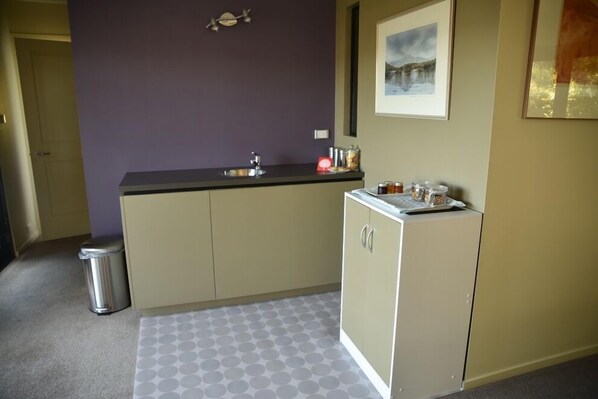 A compact kitchen with a sink, cabinets, and a trash bin. - StudioAt10 (Sandy Bay)