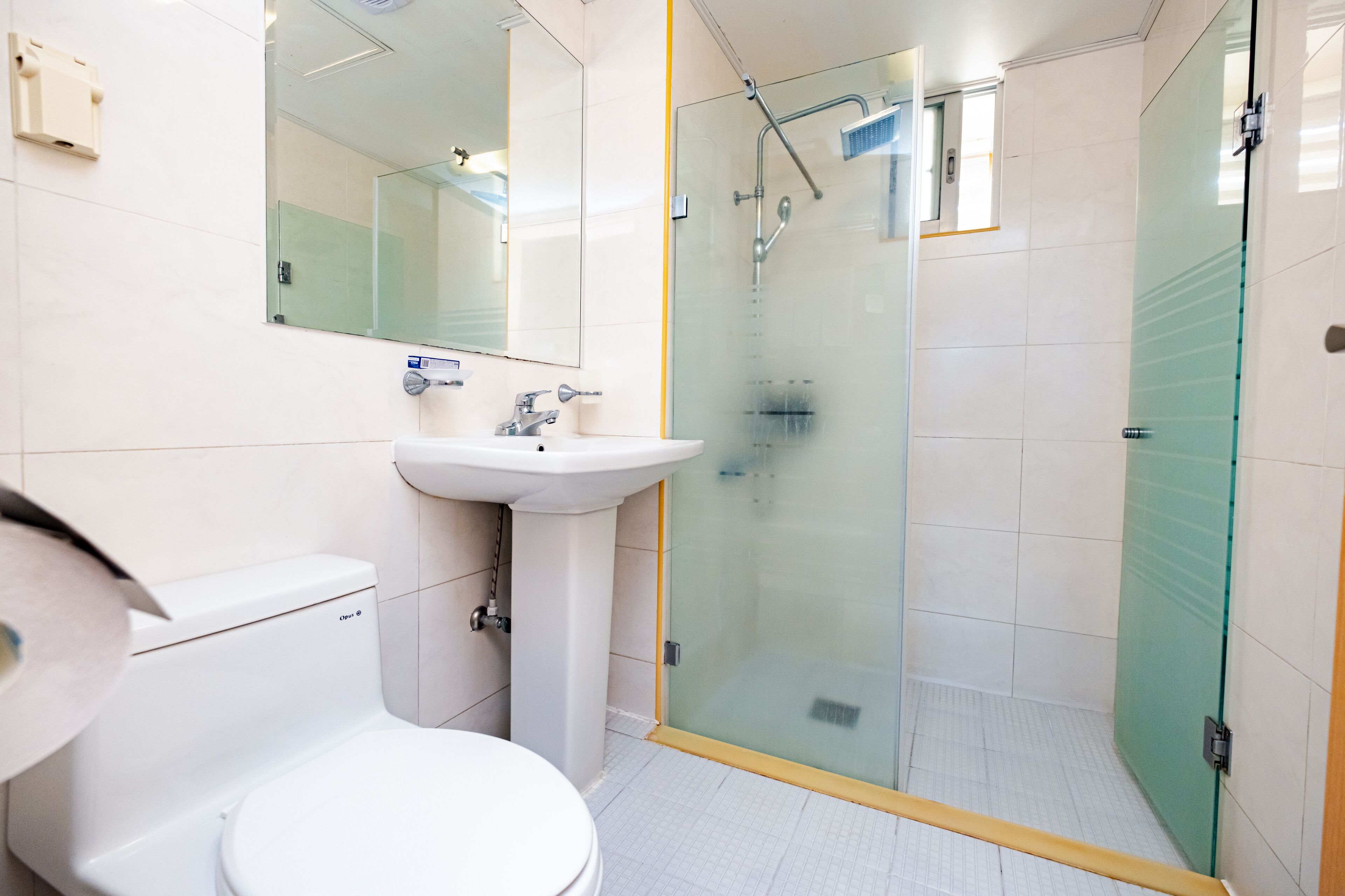 A modern bathroom with a toilet, sink, and glass-enclosed shower.