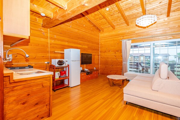 L’intérieur d’un chalet en bois comprend une cuisine, un canapé blanc et une grande fenêtre.