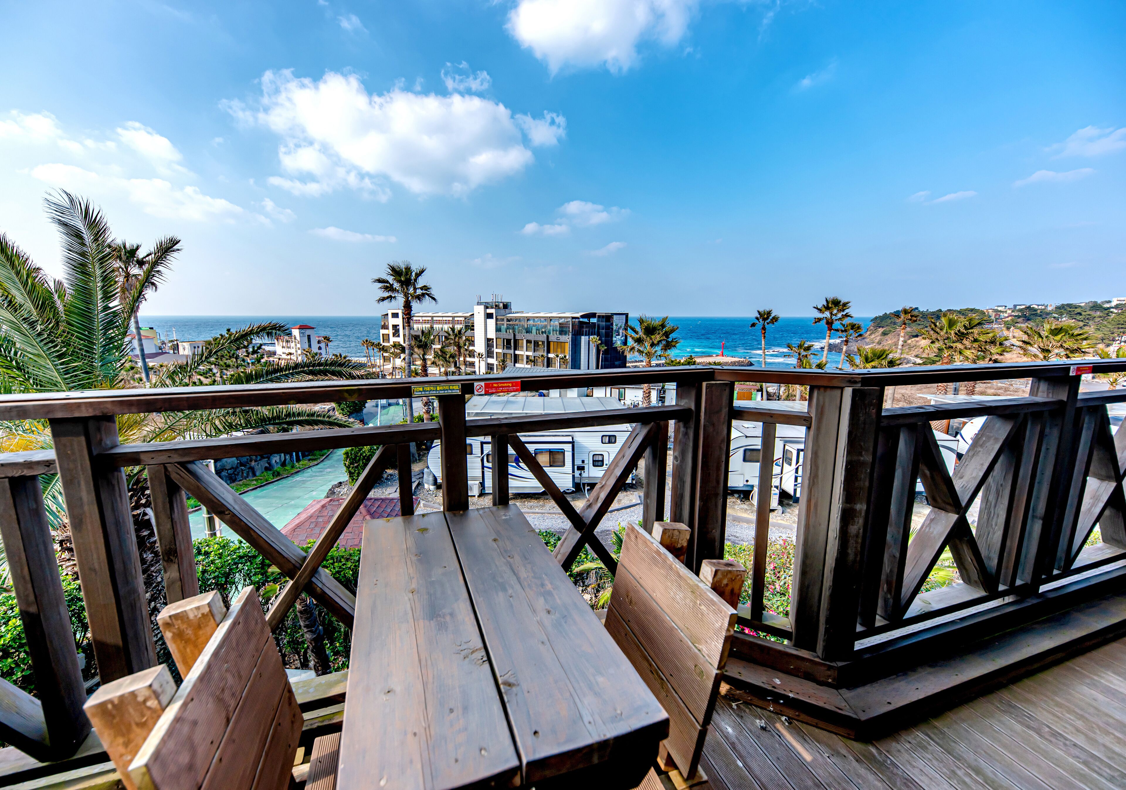 A wooden deck with a view of the ocean and buildings in the background.