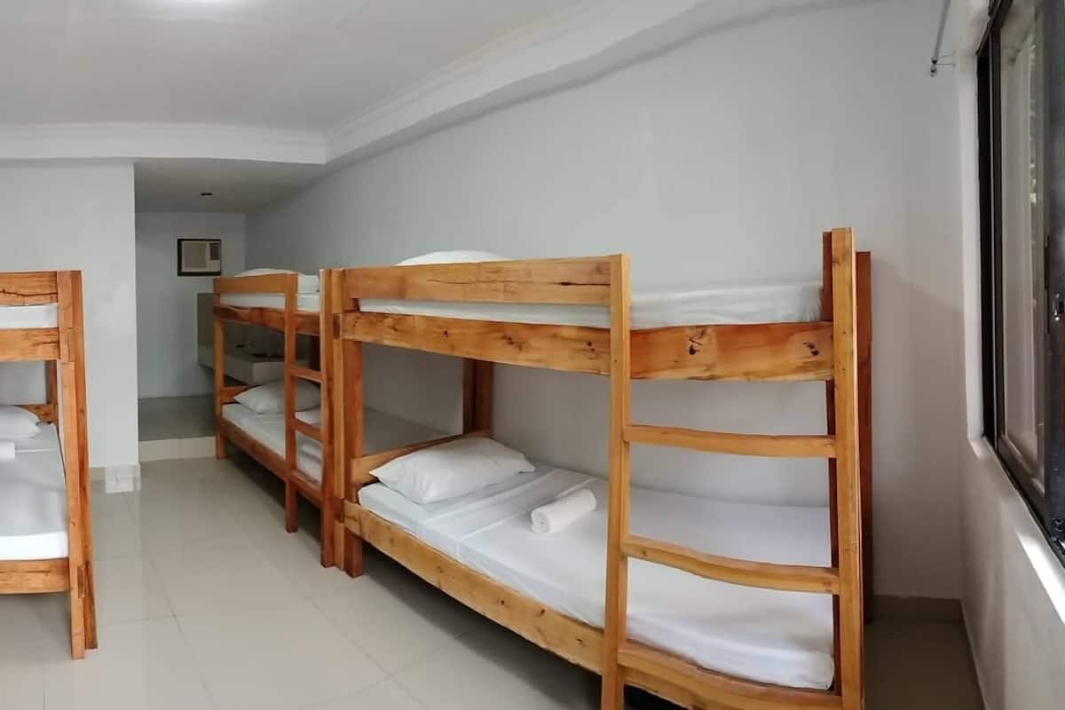 A room with bunk beds, a television mounted on the wall, and a window.