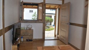 A traditional Japanese room with tatami flooring, a sliding door, a small window, and a wooden shelf with items. - Tosarang Guesthouse (Jeonju)