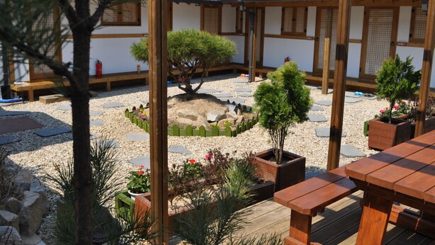 A traditional Japanese-style courtyard with wooden structures, stone pathways, and potted plants. - Tosarang Guesthouse (Jeonju)