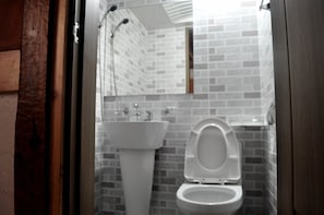 A bathroom with a white sink, a toilet, and a mirror. - Tosarang Guesthouse (Jeonju)