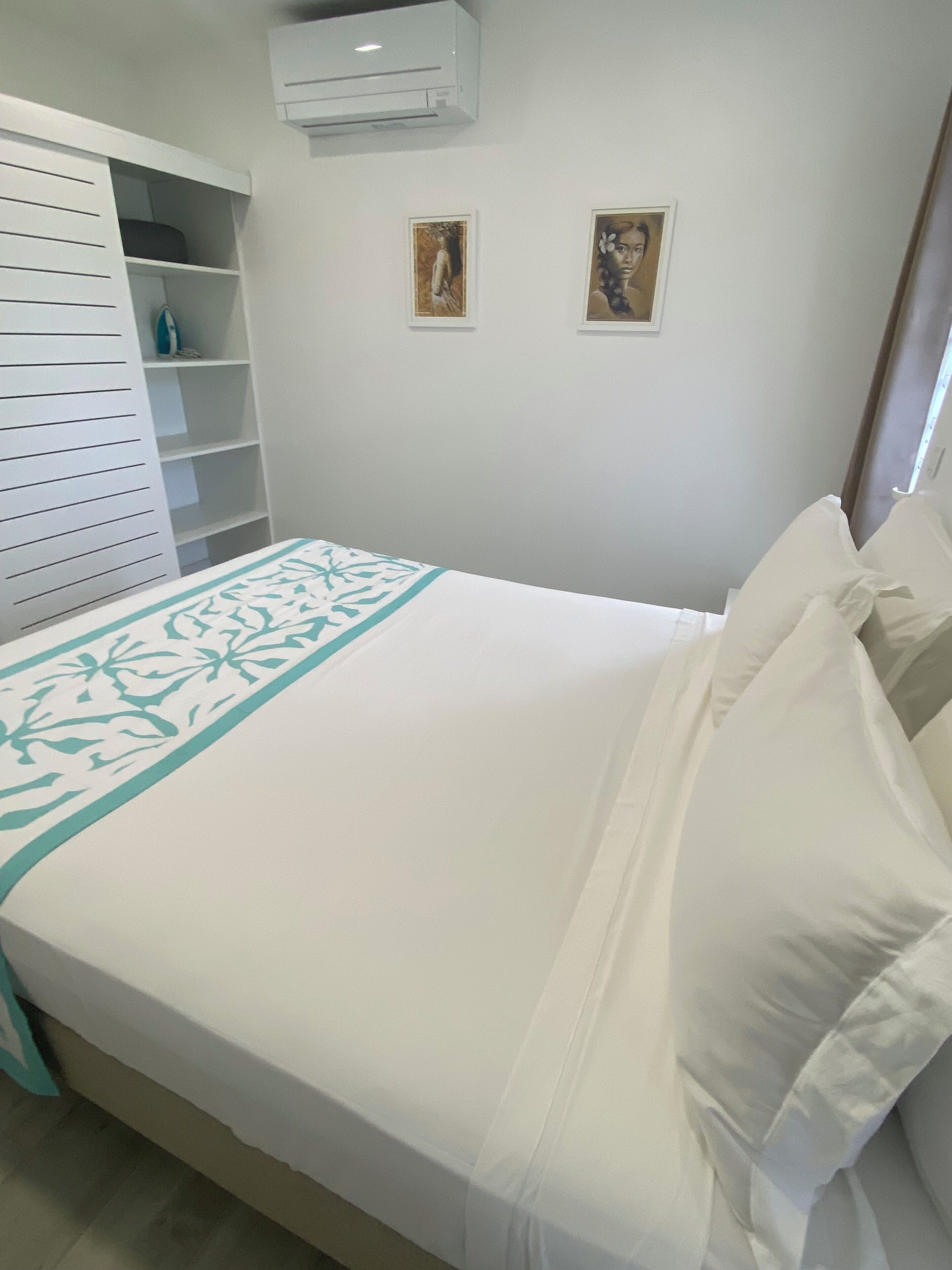 Une chambre à coucher avec un lit, une armoire et deux tableaux encadrés accrochés au mur.