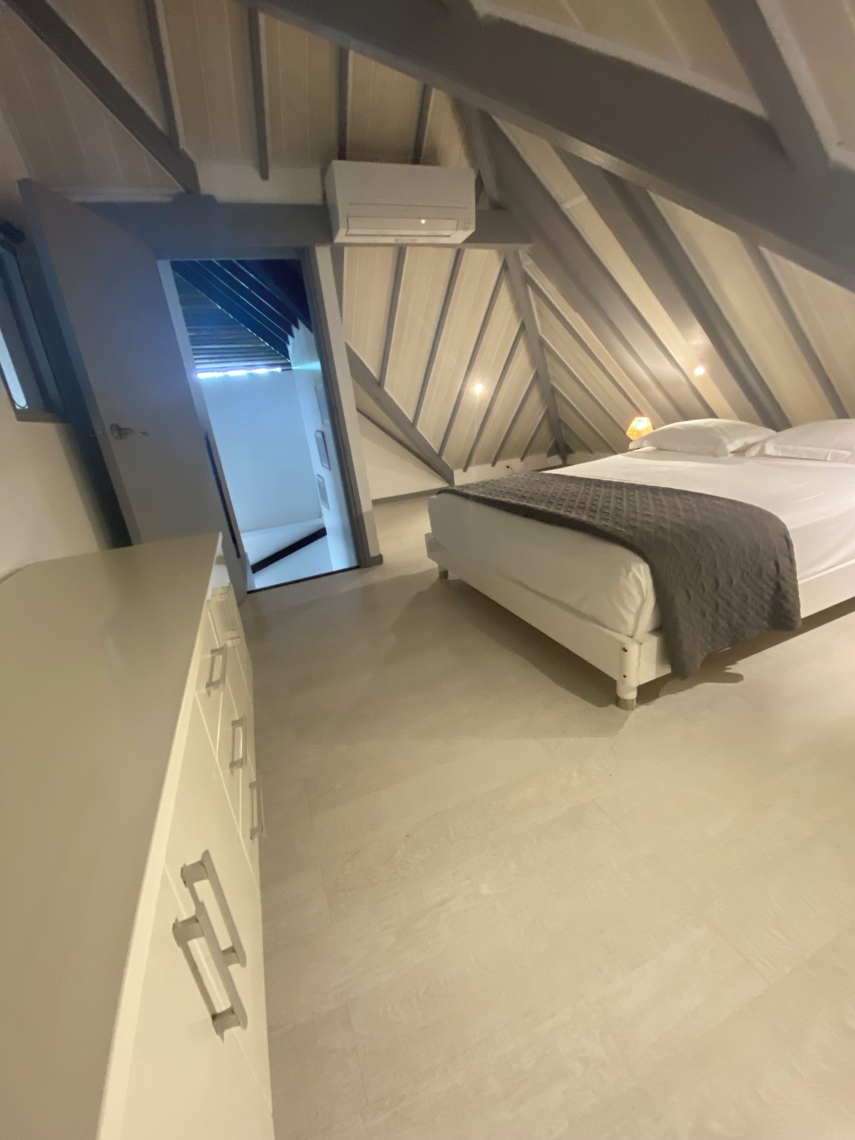 Ein modernes, kleines Zimmer mit einem Bett, einem Nachttisch und einem Deckenventilator.