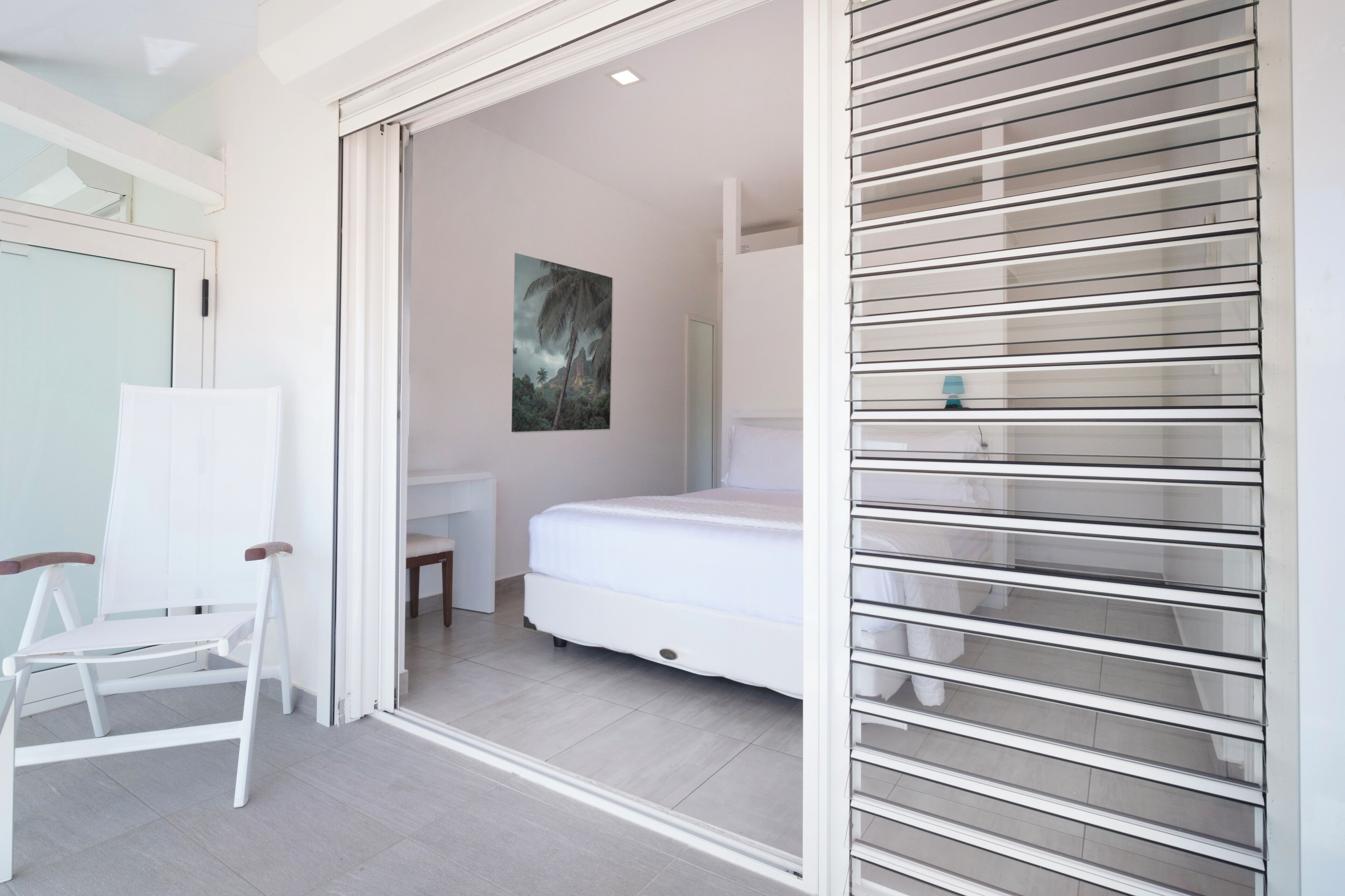 A modern bedroom with a bed, a chair, and a large window.