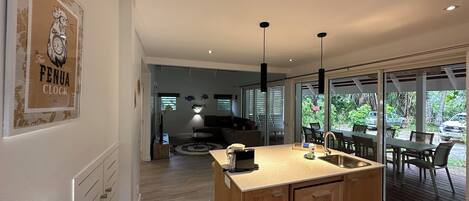 A modern kitchen with a central island, wooden cabinets, and a dining area with a view of the outdoors.