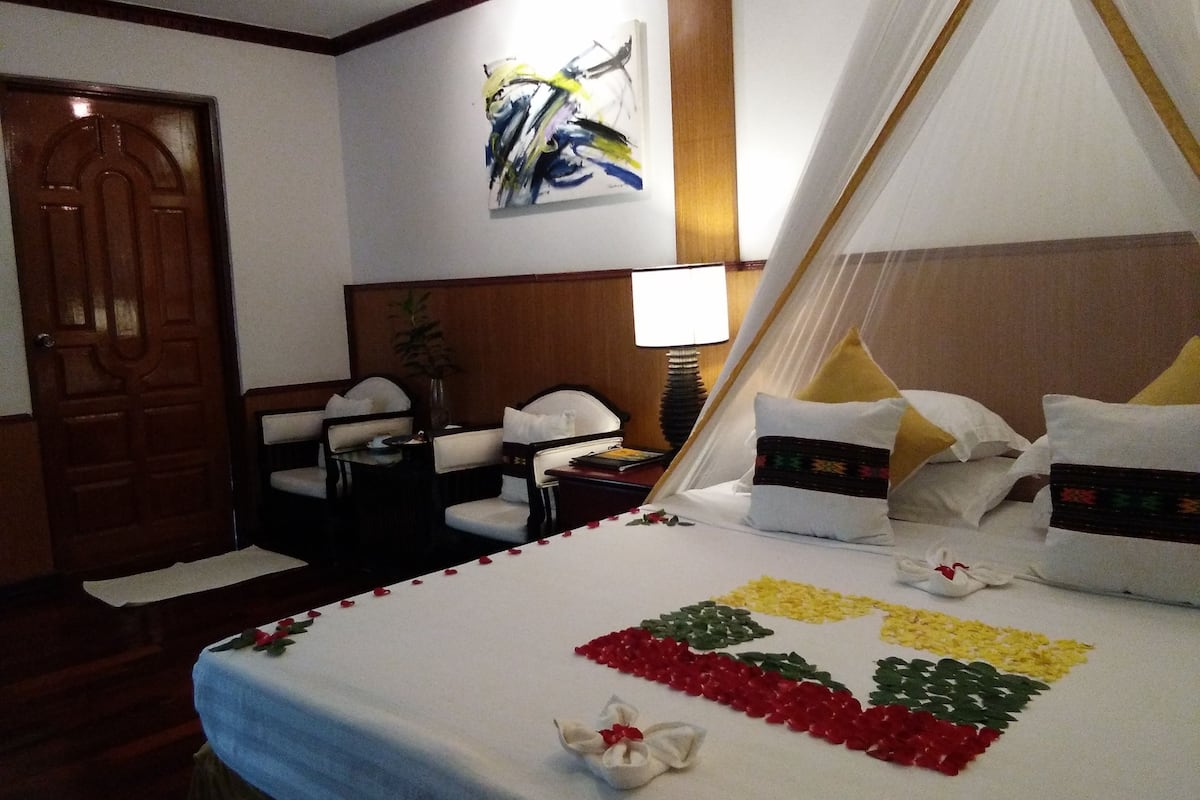 Une chambre d’hôtel avec un lit, une chaise, un bureau, une lampe et un tableau au mur.