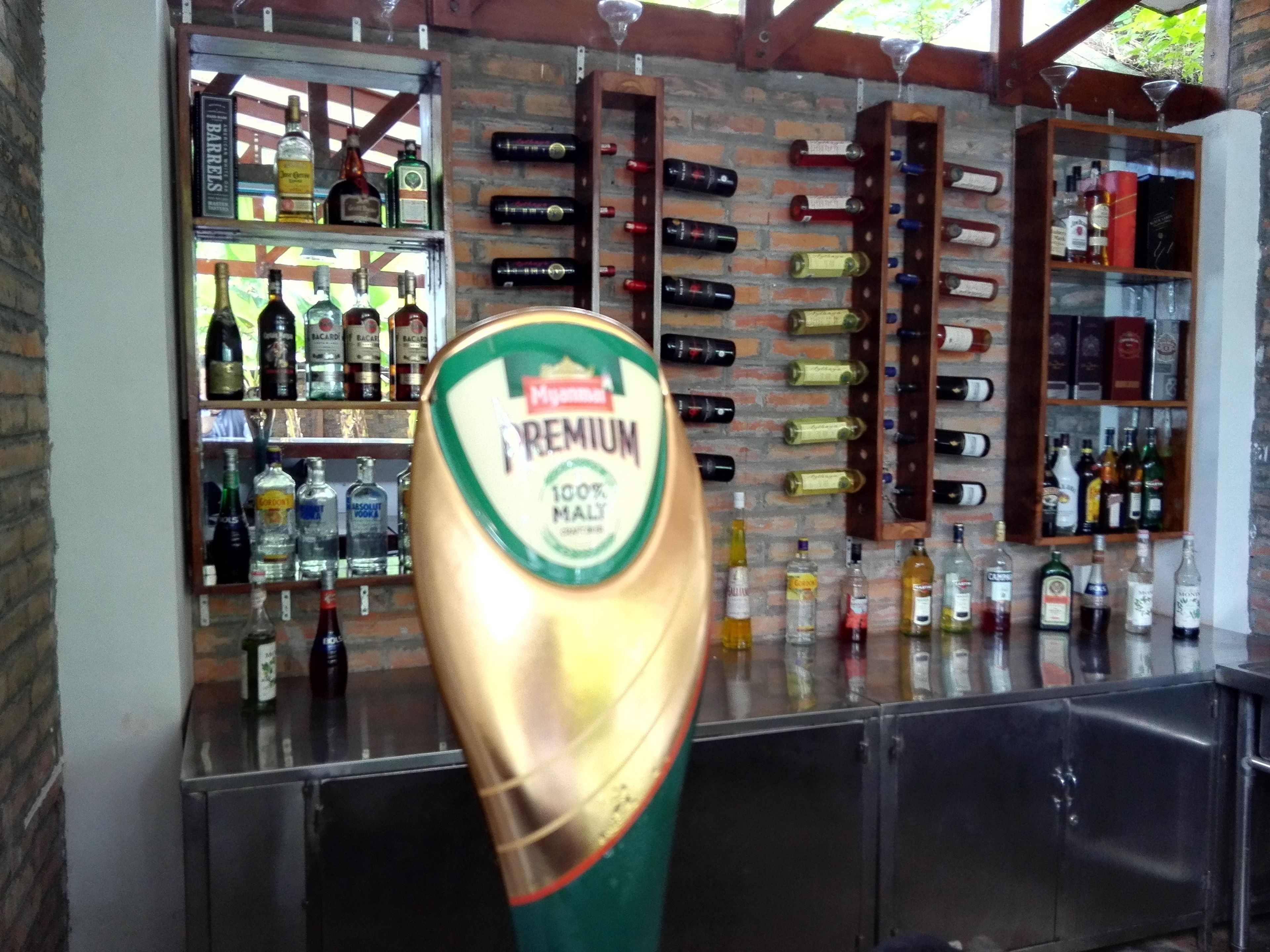 A bar area with a variety of liquor bottles on shelves and a large beer tap labeled "PREMIUM 100% MALT".