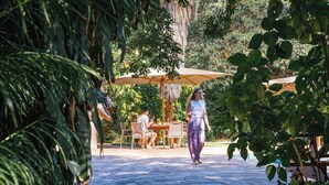 An outdoor patio area with stone flooring, tables, chairs, and umbrellas. - Bayete Guest Lodge (Victoria Falls)