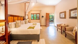 A bedroom with a large bed, bedside tables, a canopy, and a view of the outdoors. - Bayete Guest Lodge (Victoria Falls)