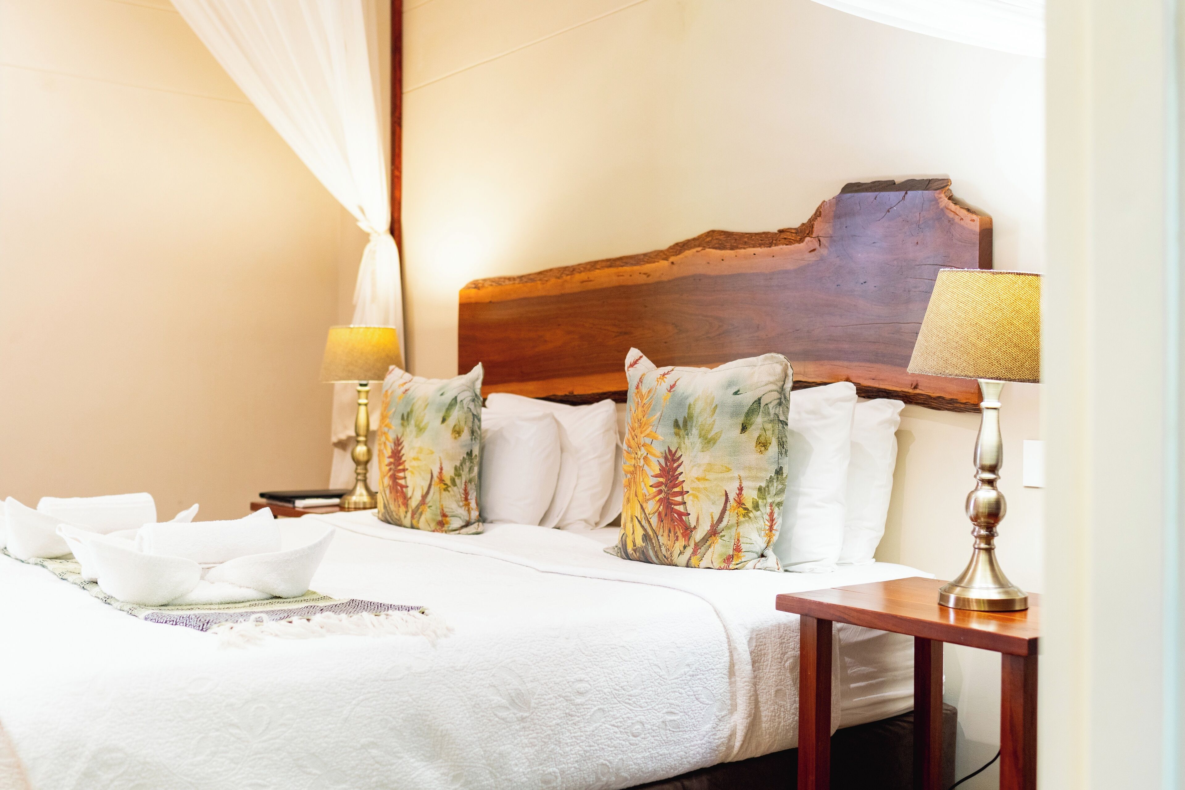 A neatly made bed with floral pillows, a wooden headboard, and bedside lamps.