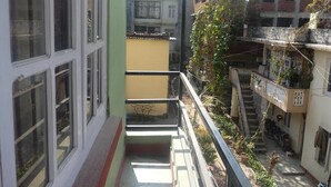 Un edificio residencial de varios pisos con balcones, una escalera y vistas a edificios vecinos.