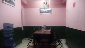 Un comedor con una mesa, sillas, un dispensador de agua y un reloj en la pared.