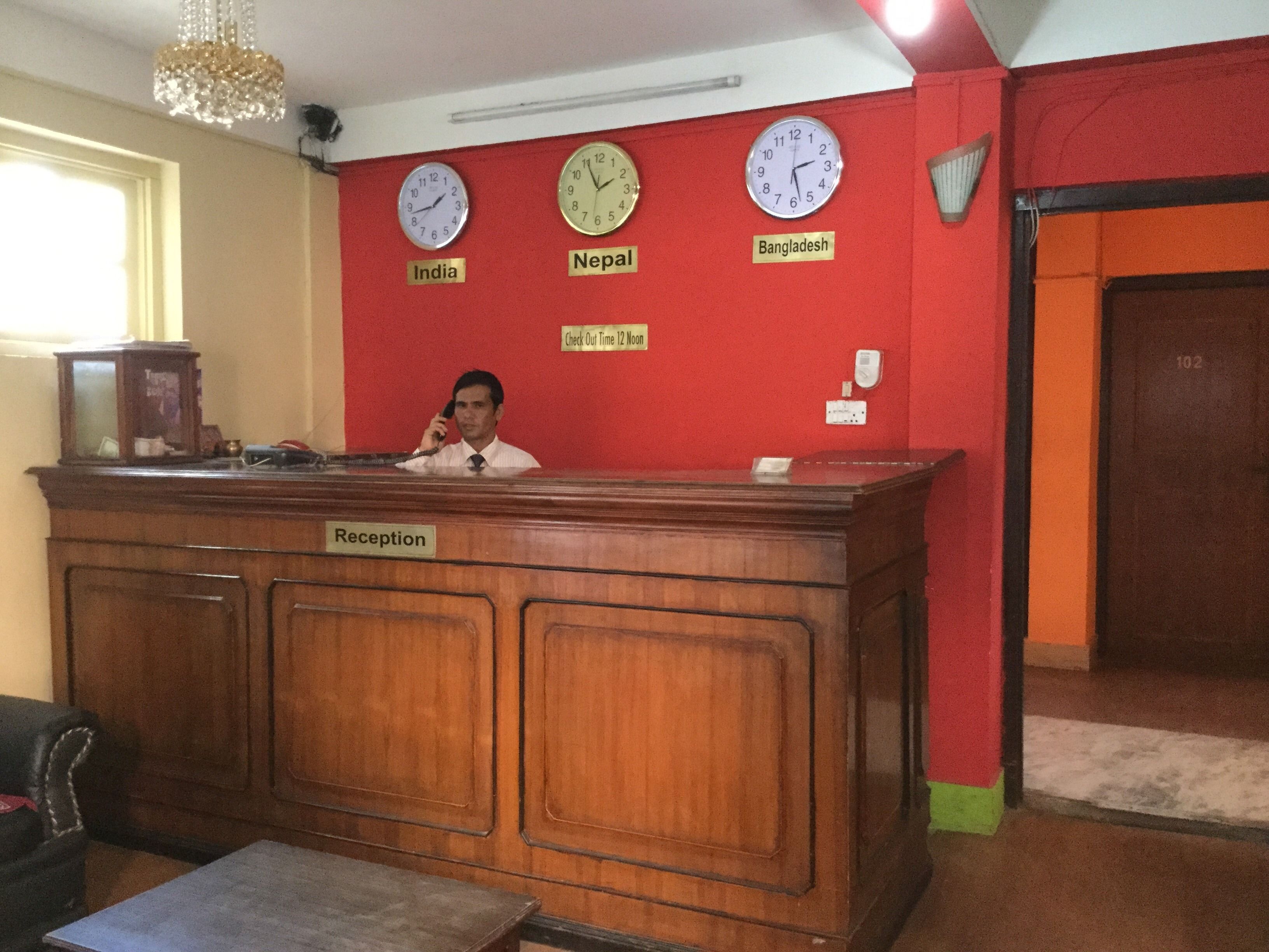 A reception desk with clocks indicating time in India, Nepal, and Bangladesh.