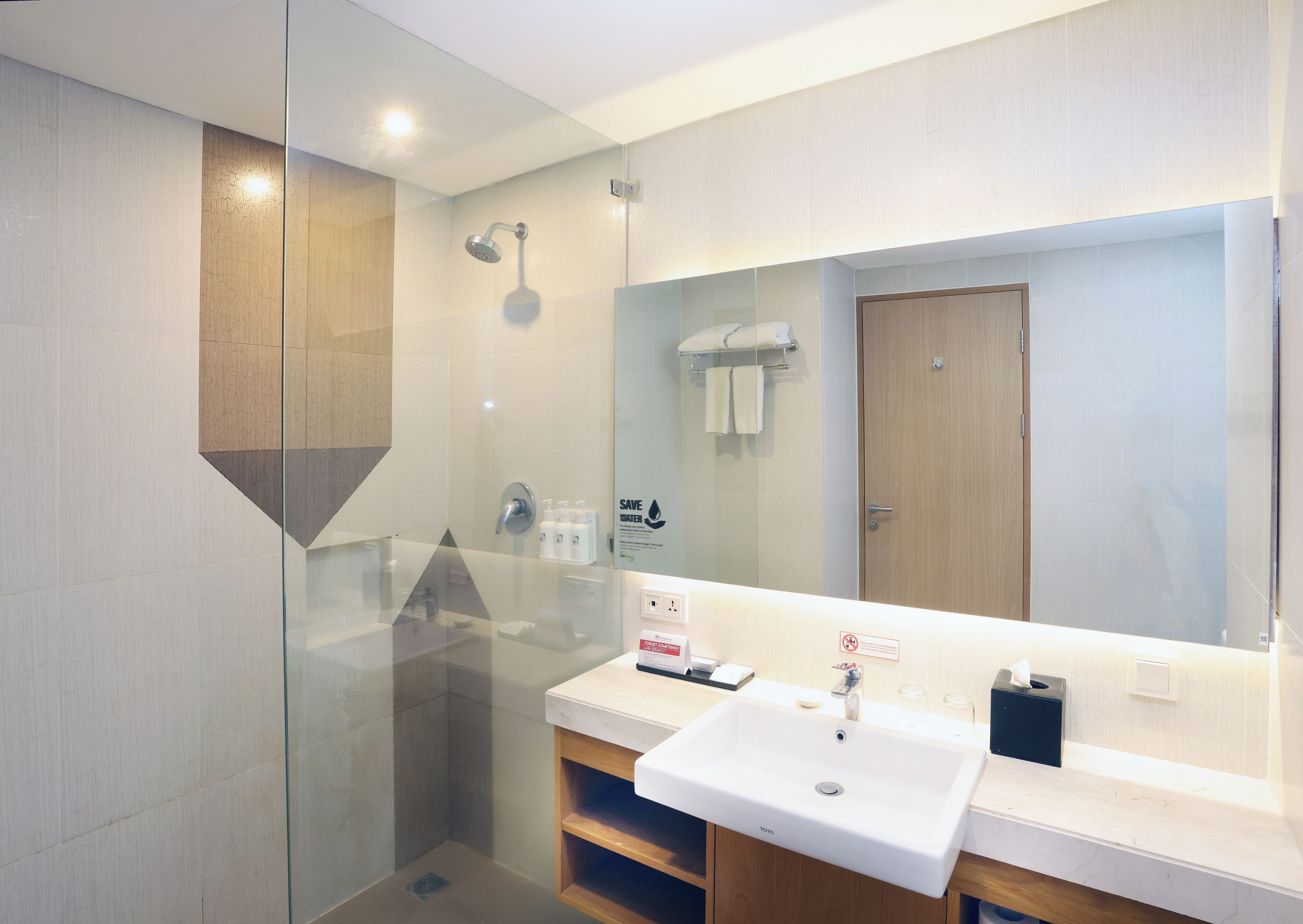 A modern bathroom with a glass-enclosed shower, a white sink, and a wooden vanity.
