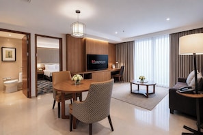Habitación de hotel con cama, televisión, escritorio, silla, mesa de centro y lámpara.
