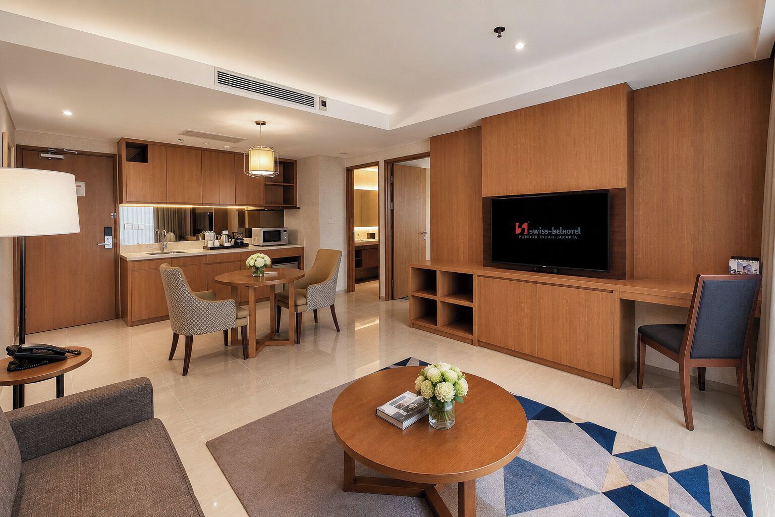 A hotel room with a dining area, a TV, and a kitchenette.