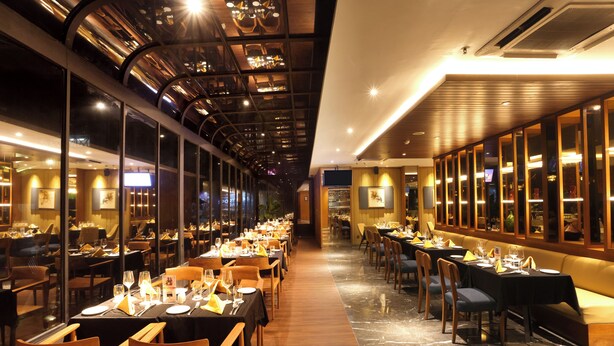 Un restaurante con mesas largas, sillas y un techo alto con luces.