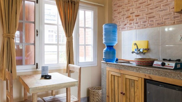 Una cocina con dispensador de agua, estufa y ventana con cortinas.