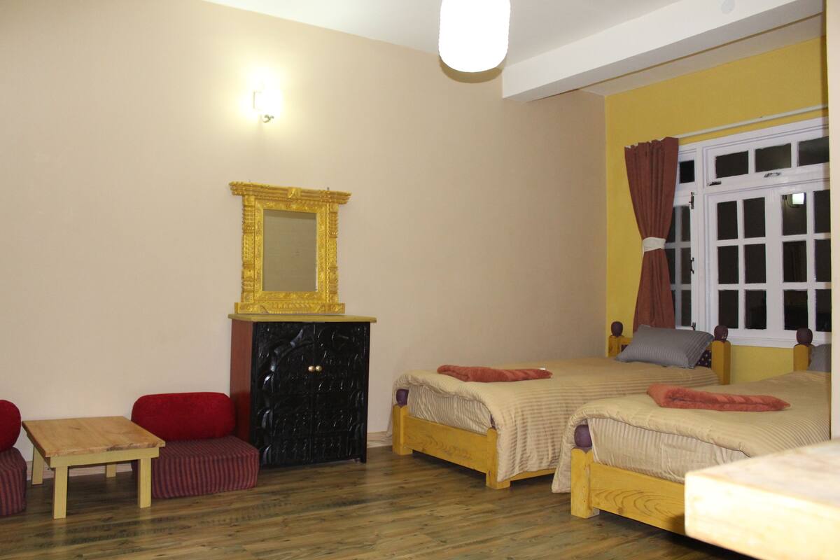 A bedroom with two beds, a wooden dresser, a small table, and a mirror.