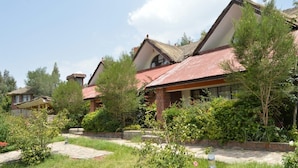 A residential building with a red roof, brick exterior, and a garden with various plants and a pathway. - Lalibela Lodge (Lalibela)