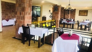 A restaurant with brick pillars, tables with white tablecloths, and a chandelier. - Lalibela Lodge (Lalibela)