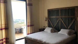 A bedroom with a large bed, a wooden headboard, and a view through a sliding door to an outdoor area. - Lalibela Lodge (Lalibela)