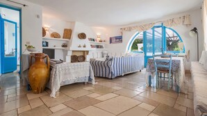 A cozy living room with a sofa, a coffee table, and a large vase. There is a window with a view of the outdoors. - La Fuggiola (San Vito dei Normanni)