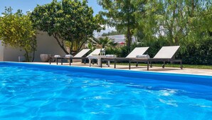 A swimming pool with lounge chairs and a stone wall. - La Fuggiola (San Vito dei Normanni)