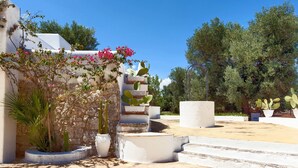 A white building with a stone wall, a staircase, and potted plants. - La Fuggiola (San Vito dei Normanni)