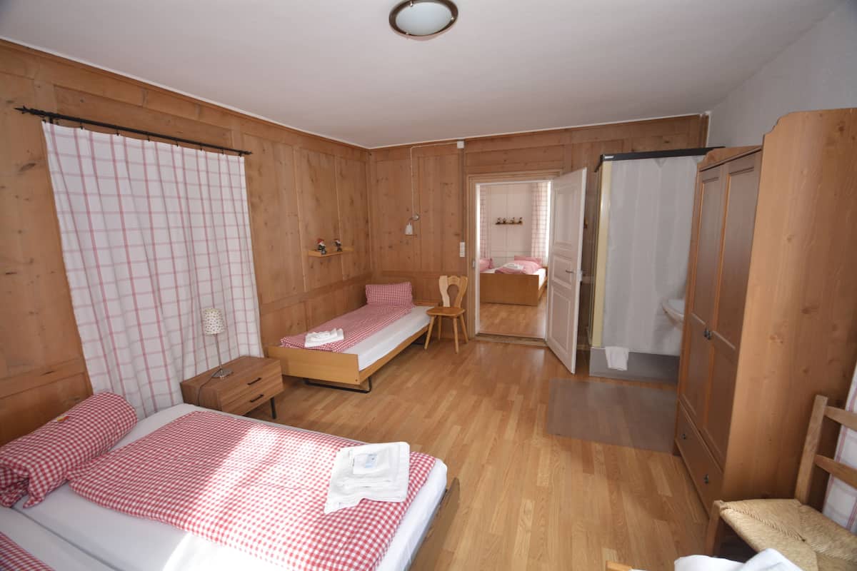Una habitación de madera con una cama, una mesita, una silla y un armario.