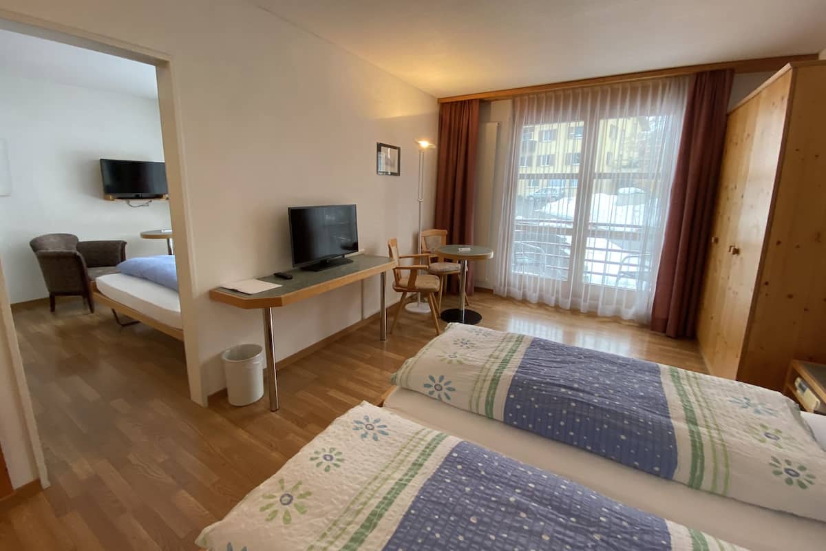 Habitación de hotel con dos camas, un escritorio, un televisor, una silla y una ventana con cortinas.