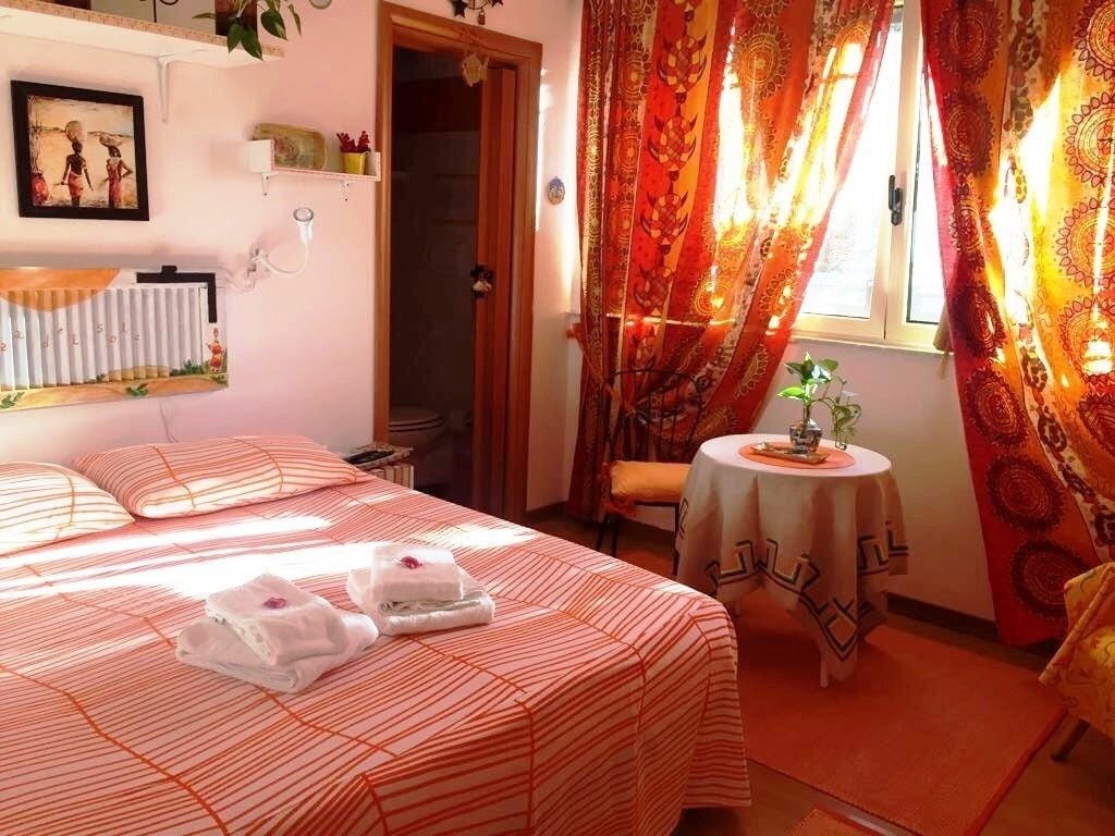 A hotel room with a bed, a small table with a tablecloth, and curtains.
