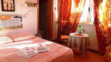 A hotel room with a bed, a small table with a tablecloth, and curtains.