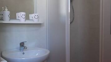 A bathroom with a sink, mirror, and shower.