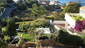 Ett bostadsområde med hus, en trädgård och utsikt över havet.