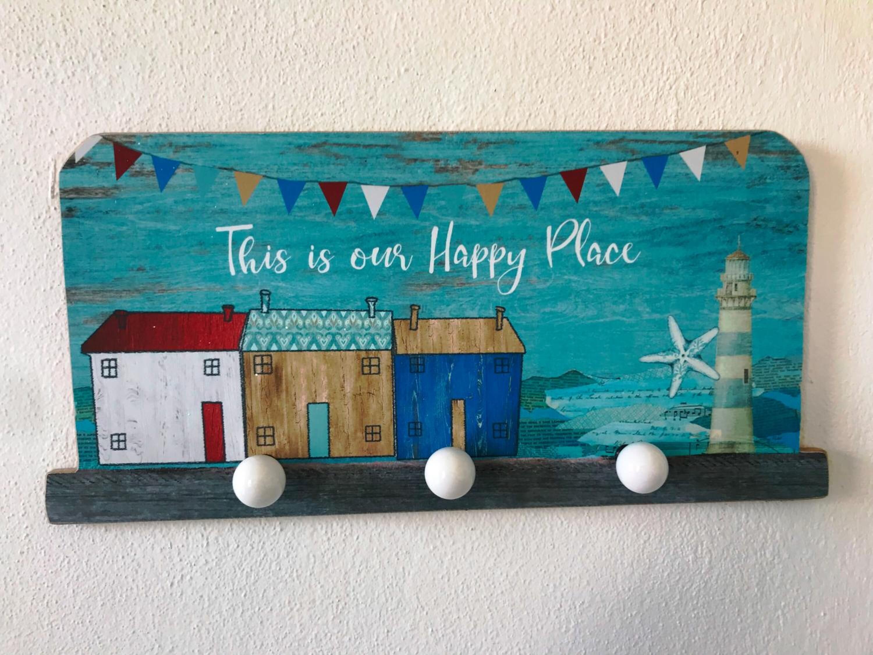 A wall-mounted sign with colorful houses and a lighthouse, stating 'This is our Happy Place.'