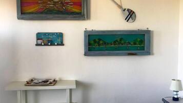 Ein Zimmer mit einer weißen Ablage, einem kleinen Tisch mit Lampe und drei gerahmten Kunstwerken an der Wand.