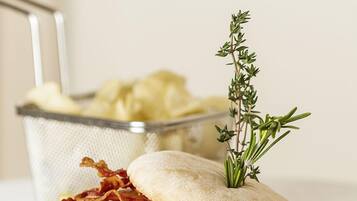 A sandwich with bacon, lettuce, tomato, and a sprig of rosemary on a white plate.