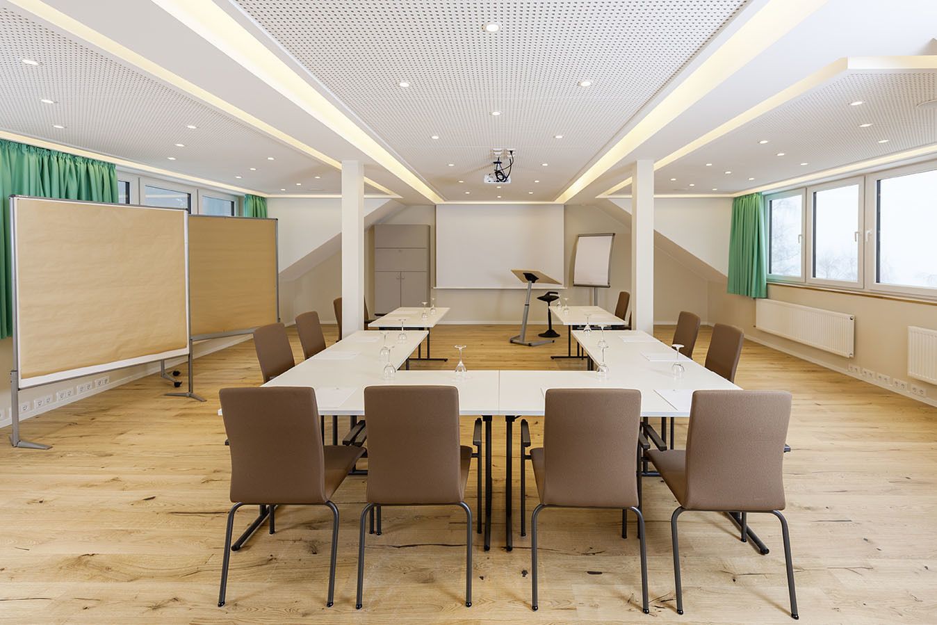 Une salle de conférence équipée d’une longue table, de chaises, d’un projecteur et d’un tableau blanc.