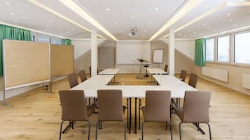 Une salle de conférence équipée d’une longue table, de chaises, d’un projecteur et d’un tableau blanc.