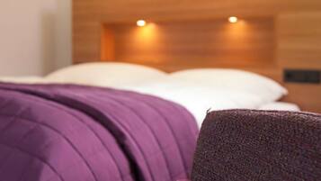 Ein Bett mit einem hölzernen Kopfteil und einer violetten Decke.