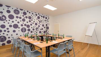 Ein Konferenzraum mit einem großen Tisch, Stühlen, einer Tafel und einer Wand mit einem Punkte-Muster.