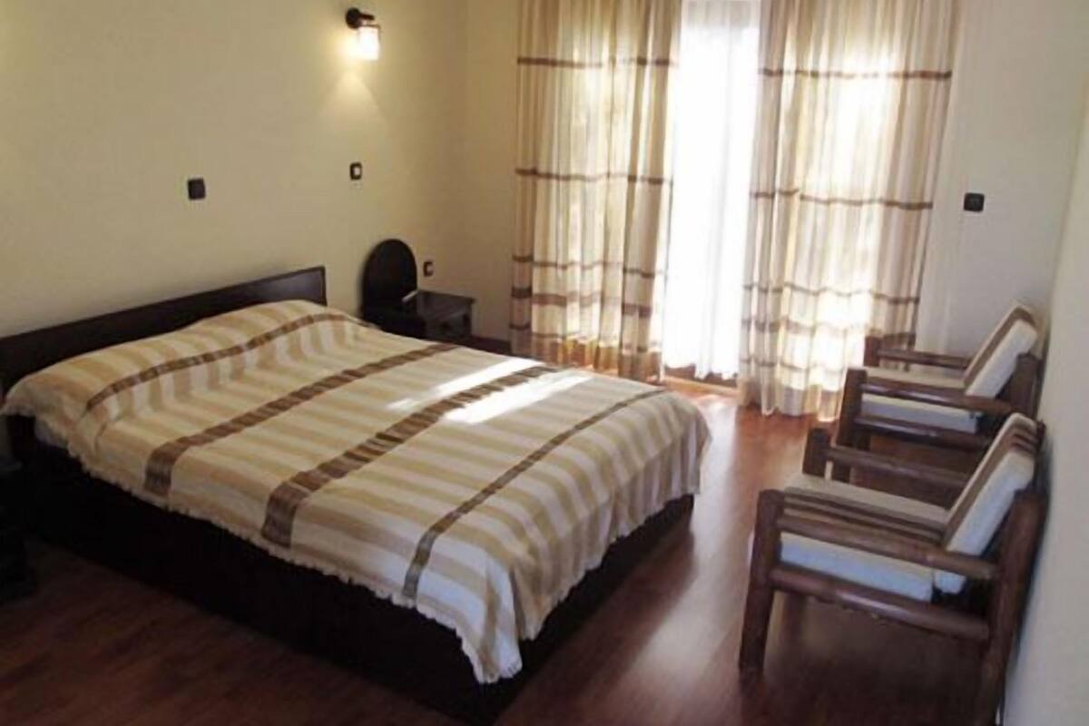 Ein Schlafzimmer mit einem großen Bett, einem Nachttisch, einem Sessel und einer Wandleuchte.