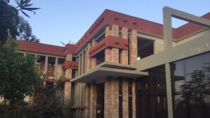 A modern building with a red roof, large glass windows, and a stone facade.