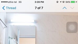 A bathroom with a sink, mirror, toilet, and a trash bin.