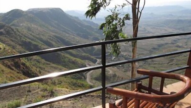 A wooden bench with a view of a mountainous landscape.