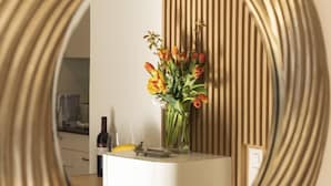 A round mirror with a ribbed frame reflecting a kitchen area with a white countertop, a vase of flowers, and wooden paneling on the wall.